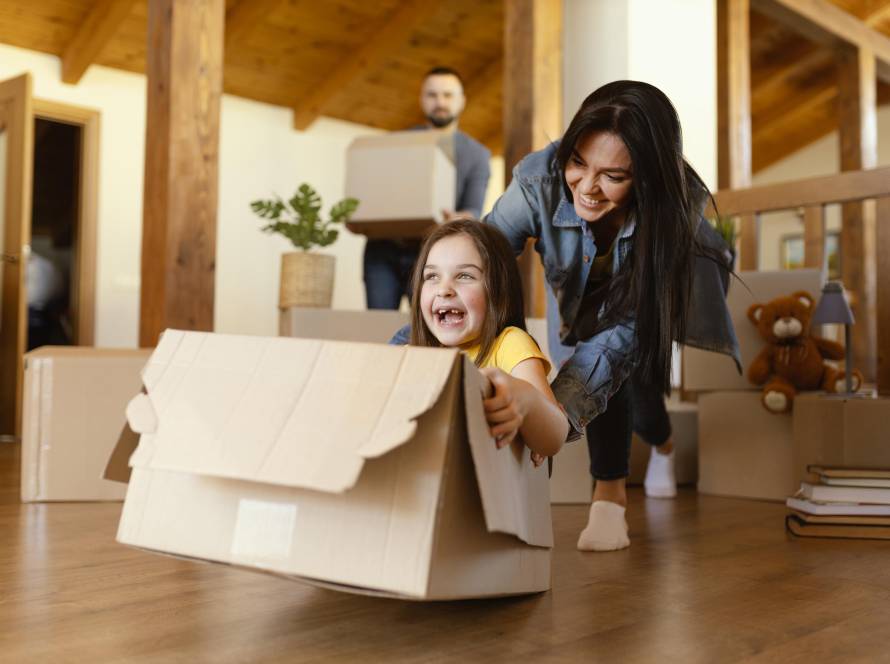 girl sitting in cardboard box playing with her mother.