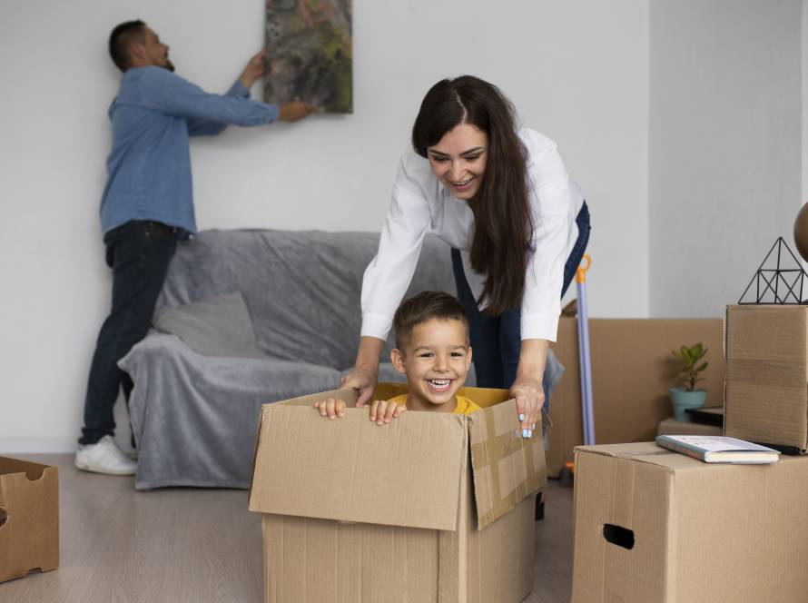 boy sitting in a cardboard box playing with her mother.