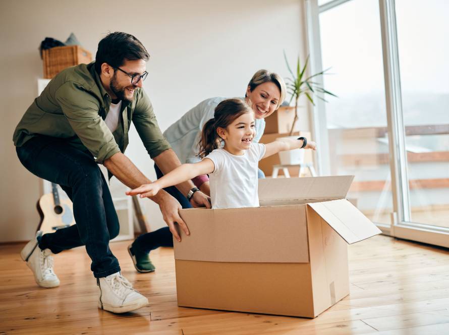 a small girl in cardboard box playing with her parents.